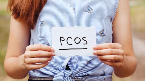 woman holding a white paper with PCOS text written